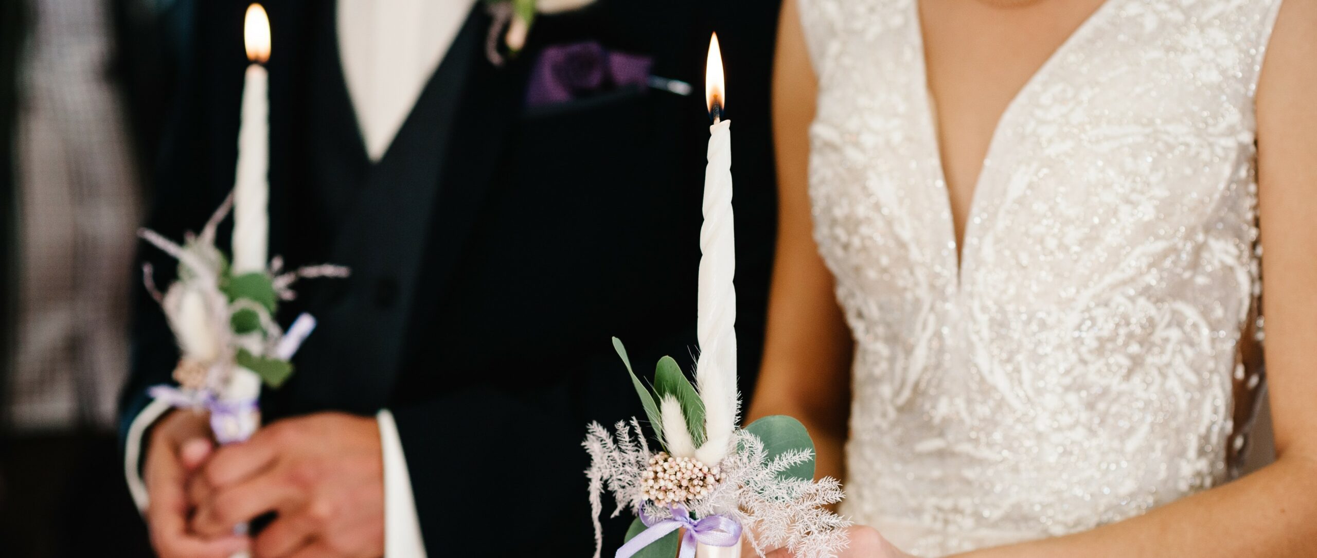 Brautpaar hält Kerzen in der Hand bei Hochzeitszeremonie