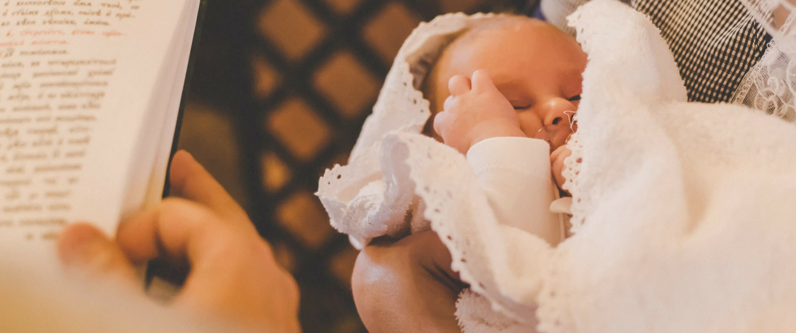 Pfarrei Taufe Pfarrer liest auf der Bibel vor und Kind ist in den Armen eines Elternteils