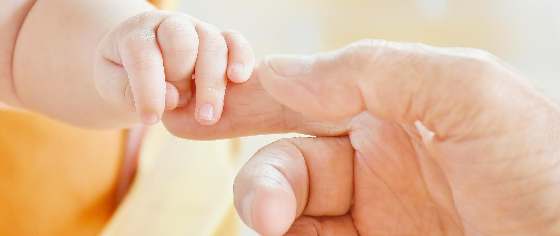 Pfarrei Taufe Kind hält Hand von Pfarrperson